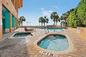 Ein Poolbereich mit mehreren Pools, Liegestühlen und Palmen.