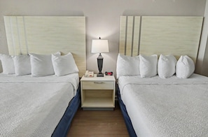 A hotel room with two beds, a nightstand with a lamp, a phone, and a digital clock. - Oceanfront Studio w/ Two Queens + Beach & Pools (Myrtle Beach)