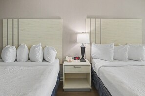 A hotel room with two beds, a nightstand with a lamp, a phone, and a digital clock. - Oceanfront Studio w/ Two Queens + Beach & Pools (Myrtle Beach)