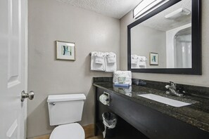 A bathroom with a toilet, sink, mirror, and towels. - Oceanfront Studio w/ Two Queens + Beach & Pools (Myrtle Beach)