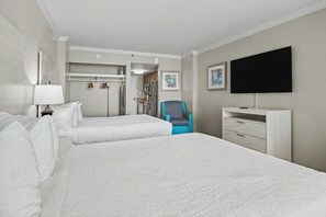 Quarto de hotel com duas camas, uma televisão, escrivaninha e uma cadeira.