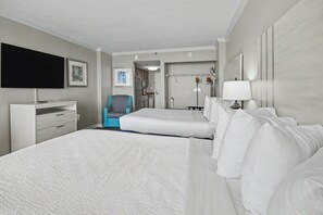 Ein Hotelzimmer mit einem großen Bett, einem Schreibtisch, einem Sessel, einem Fernseher und einem durchgegangenen Badezimmer.