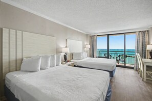 A hotel room with two beds, a desk, and a balcony with a view of the sea. - Oceanfront Studio w/ Two Queens + Beach & Pools (Myrtle Beach)
