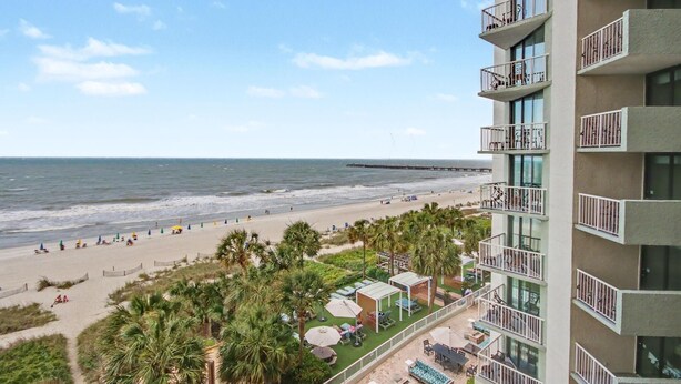 A high-rise hotel with balconies overlooking a beach, a pool area, and a view of the ocean. - Oceanfront Studio w/ Two Queens + Beach & Pools (Myrtle Beach)