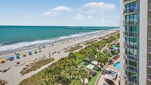 A beach resort with a pool, beach umbrellas, and a pier. - Oceanfront Studio w/ Two Queens + Beach & Pools (Myrtle Beach)