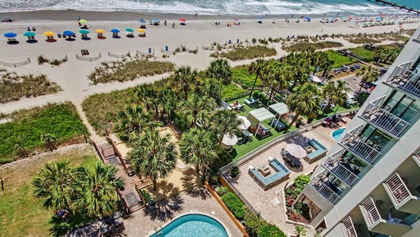 A resort with a swimming pool, beach, and palm trees. - Oceanfront Studio w/ Two Queens + Beach & Pools (Myrtle Beach)