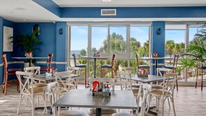 A restaurant with outdoor seating, large windows, and a view of palm trees. - Ocean View King Room + Beach Access + Lazy River (Myrtle Beach)