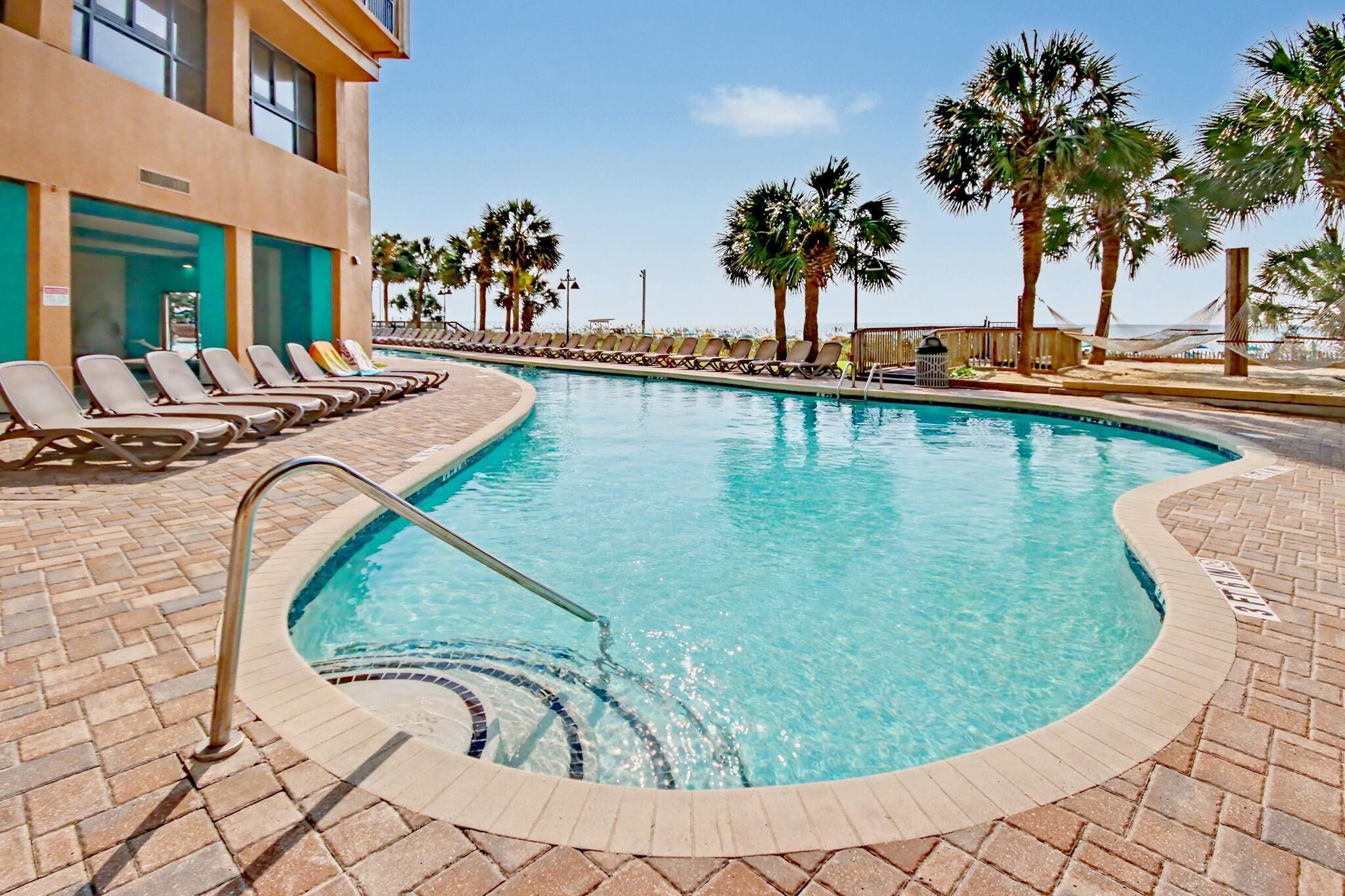 A swimming pool with lounge chairs and palm trees.