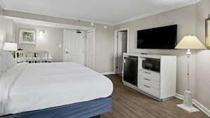 Una camera da letto con un letto, una televisione, un frigorifero, una scrivania e sedie.