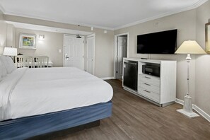 A bedroom with a bed, a television, a refrigerator, a desk, and chairs. - Ocean View King Room + Beach Access + Lazy River (Myrtle Beach)
