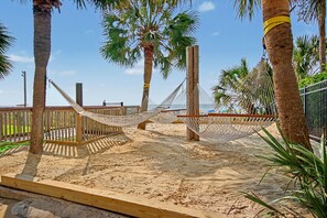 Een zandstrand met hangmatten en houten constructies.