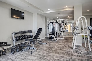 A gym with weightlifting equipment, dumbbells, and a TV on the wall. - Ocean View King Room + Beach Access + Lazy River (Myrtle Beach)
