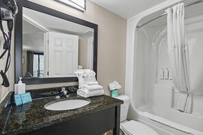 A bathroom with a sink, mirror, and shower. - Ocean View King Room + Beach Access + Lazy River (Myrtle Beach)