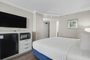 A hotel room with a bed, a flat-screen TV, a microwave, and a refrigerator. - Ocean View King Room + Beach Access + Lazy River (Myrtle Beach)