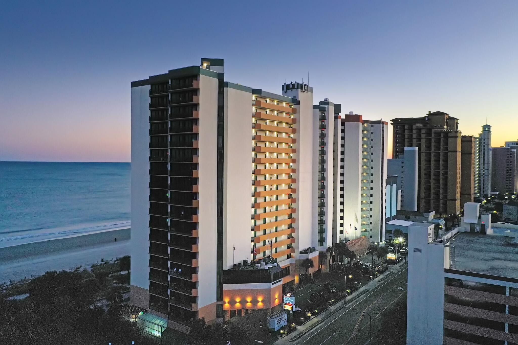 Ein Hochhotel mit mehreren Etagen, Blick auf den Strand und einem Parkplatz.