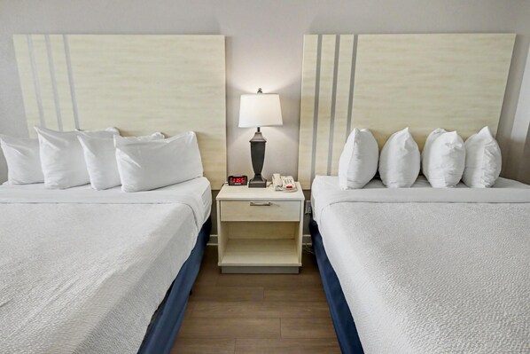 A hotel room with two beds, a nightstand with a lamp, a phone, and a digital clock. - Oceanfront Studio w/ Two Queens + Beach & Pools (Myrtle Beach)