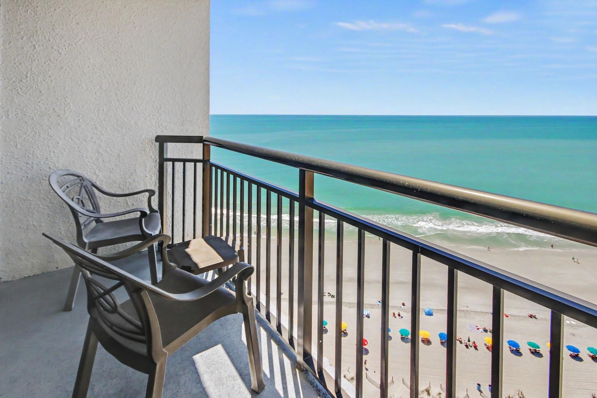 A balcony with a view of the beach and ocean.
