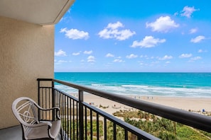 A balcony with a view of the ocean and beach, a chair, and a railing. - Oceanfront w/ Balcony & Kitchen | Dog Friendly (Myrtle Beach)