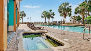A swimming pool with a 3 FT depth marker, surrounded by lounge chairs and palm trees. - Oceanfront Studio w/ Two Queens + Beach & Pools (Myrtle Beach)