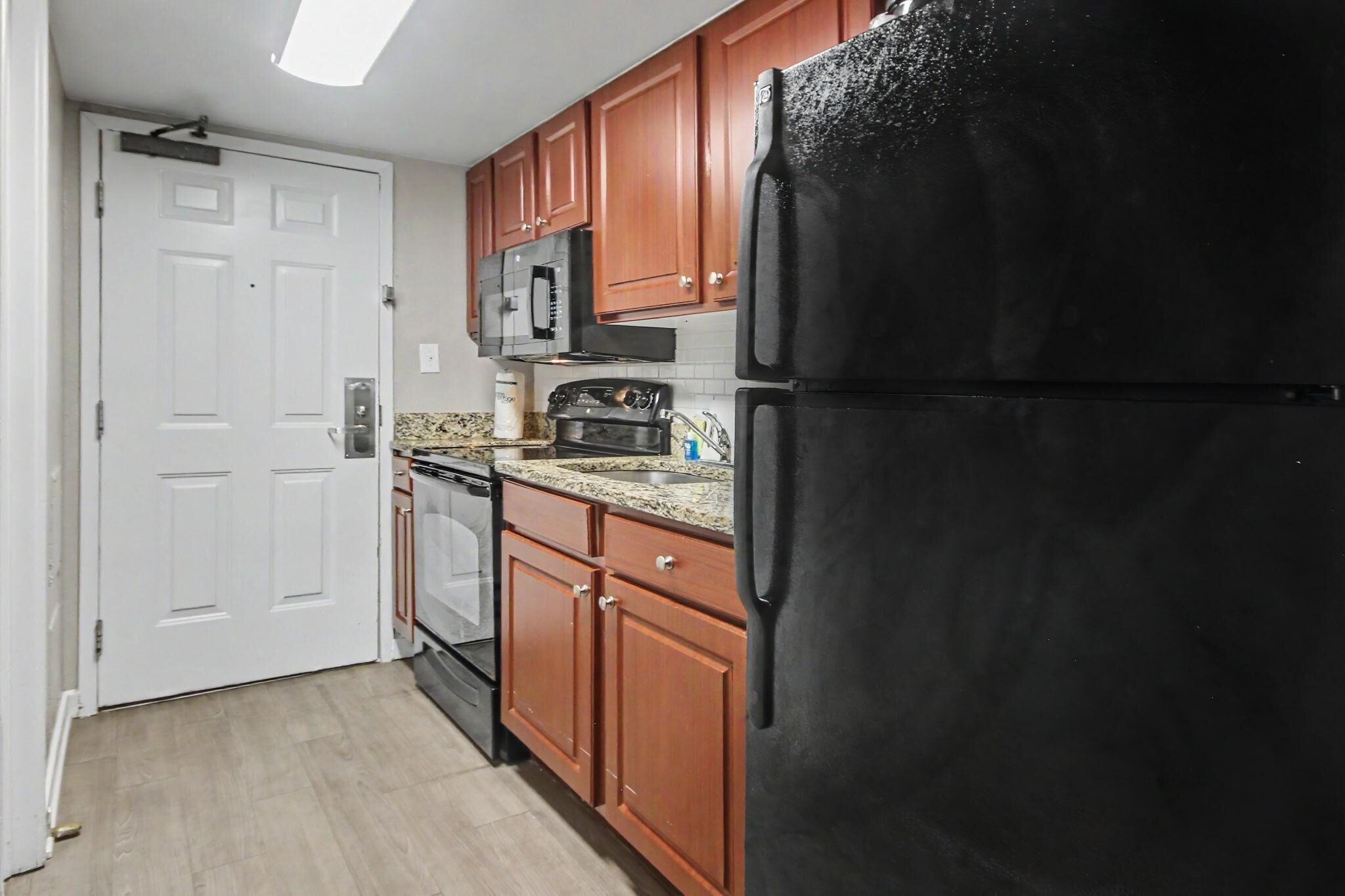 A kitchen with wooden cabinets, a black refrigerator, a microwave, and a stove.