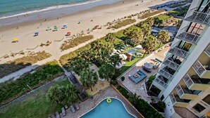 Un hotel con piscina, vista a la playa y zona de estar al aire libre.