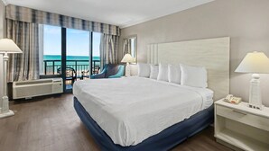 A hotel room with a large bed, two bedside lamps, a nightstand with a phone, a chair, and a view of the ocean. - Ocean View King Room + Beach Access + Lazy River (Myrtle Beach)