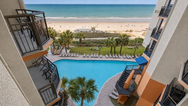 A pool with a view of the beach, a staircase, and lounge chairs. - Ocean View King Room + Beach Access + Lazy River (Myrtle Beach)