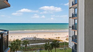A beachfront hotel with a view of the ocean, beach umbrellas, and palm trees. - Ocean View King Room + Beach Access + Lazy River (Myrtle Beach)
