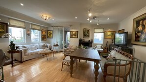 Ein geräumiges Wohnzimmer mit einem Holzesstisch, Sofas und einem Fernseher.