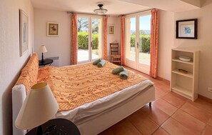 Ein Schlafzimmer mit Bett, Stuhl, Schreibtisch, Lampe und Regal.