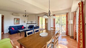 Un comedor con una mesa y sillas de madera, un sofá azul y una araña.