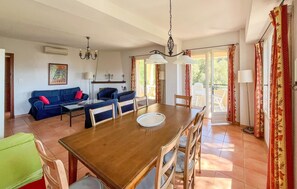 Ein Essbereich mit Holztisch und -stühlen, einem blauen Sofa und einer Chandelier.