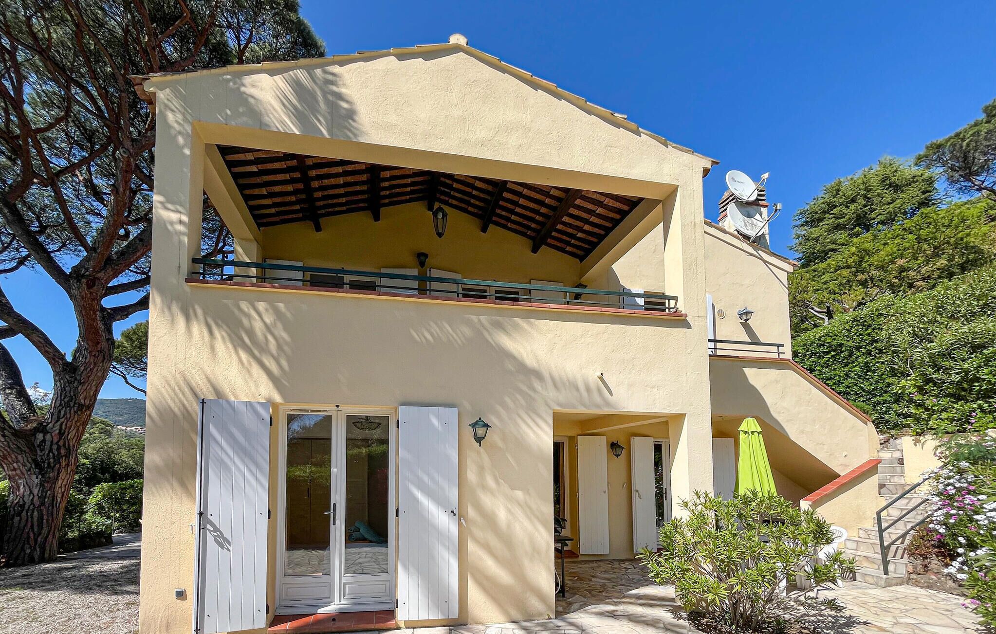 A two-story building with a balcony, a satellite dish, and a small garden area.