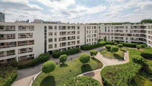 A multi-story residential building with balconies, a central courtyard with trees, and a clear sky. - Kolska Charming Apartment (Warszawa)