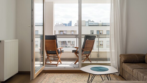 A balcony with two wooden chairs, a small table, and a sofa. - Kolska Charming Apartment (Warszawa)