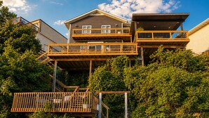 Uma casa de vários andares com um deck de madeira e uma ponte sobre a água.