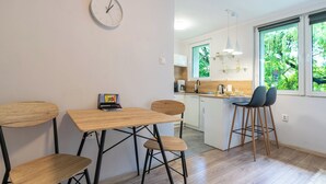Una cucina moderna con zona pranzo, un orologio al muro e una finestra vista su piante.