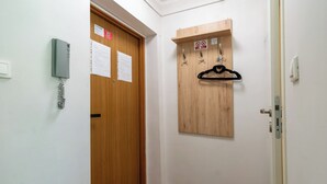 Un corridoio con una porta in legno, un attaccapanni e un telefono fissato al muro.