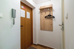 A hallway with a wooden door, a coat rack, and a wall-mounted telephone. - Gorzołki Comfort Studio (Gliwice)