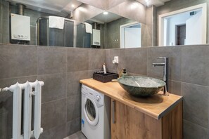 A modern bathroom with a built-in washing machine, a large basin sink, and a towel rack. - Cichociemnych Chic Studio (Gliwice)