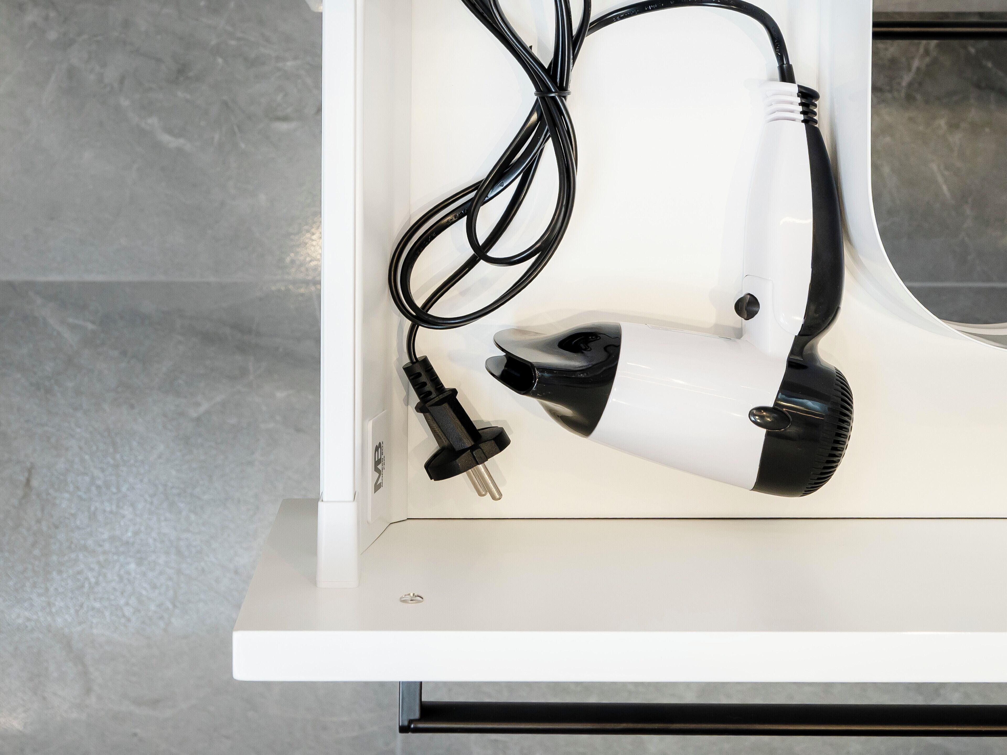 A white hairdryer with a black cord and plug on a white surface.