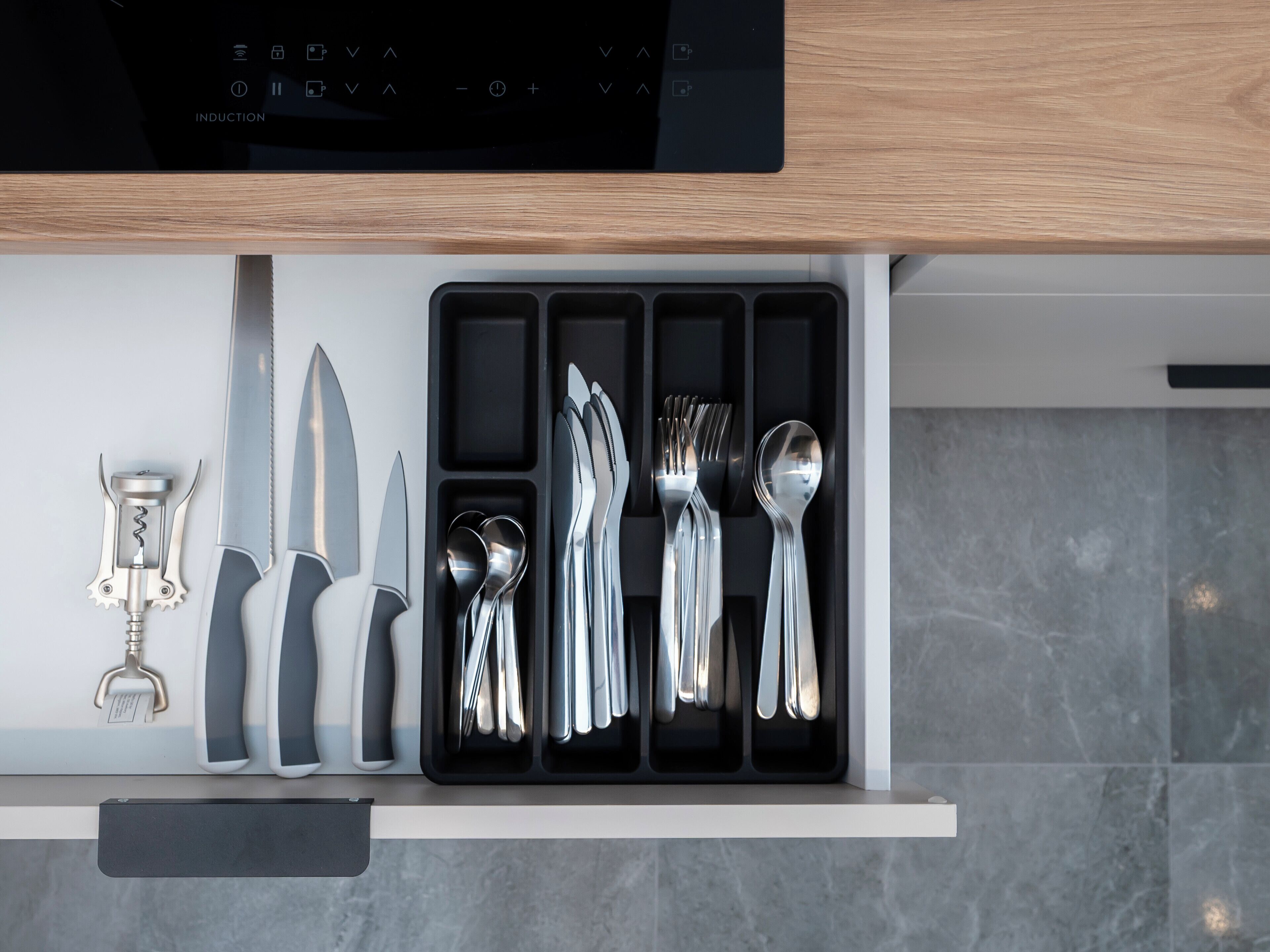 Un cassetto della cucina con utensili da cucina e cavatappi.