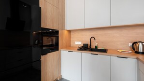 Eine moderne Küche mit einem schwarzen Kühlschrank, einem eingebauten Backofen, einer Edelstahl-Spüle und einer Holzarbeitsplatte.