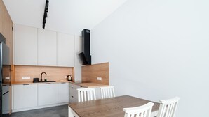 Eine moderne Küche mit weißen Schränken, einer Holzausziehtischplatte und einem Essbereich mit einem Holztisch und weißen Stühlen.