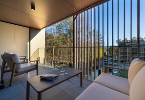 Ein moderner Balkon mit einer Couch, einem Tisch und einem Stuhl, mit Blick auf eine Wohngegend.