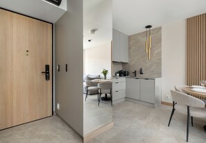 Eine moderne Küche mit Essbereich, einer Holztür und Blick in das Wohnzimmer.