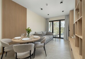 Ein moderner Essbereich mit rundem Tisch, Stühlen und einer Couch im Hintergrund.