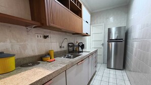 Una cocina con un refrigerador de acero inoxidable, un lavamanos y una encimera con varios objetos.