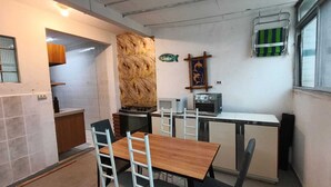 Cocina compacta con una mesa y sillas de madera, estufa, tostadora y un refrigerador pequeño.