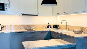 A modern kitchen with grey cabinets, a black pendant light, a built-in microwave, and a granite countertop. - Family Apartment for 4 by the Water (Dziwnów)